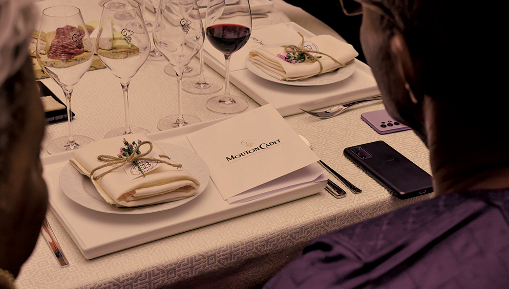 a person sitting at a table with wine glasses and a plate of food