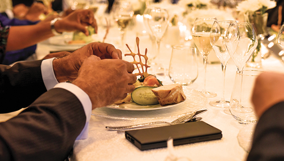 a person's hands on a plate with food and glasses